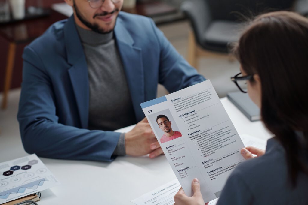 Mann in einem Vorstellungsgespräch gegenüber der Personalerin mit seinem Lebenslauf in der Hand