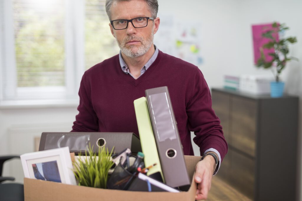 Mann verlässt enttäuscht das Büro mit gepackter Kiste